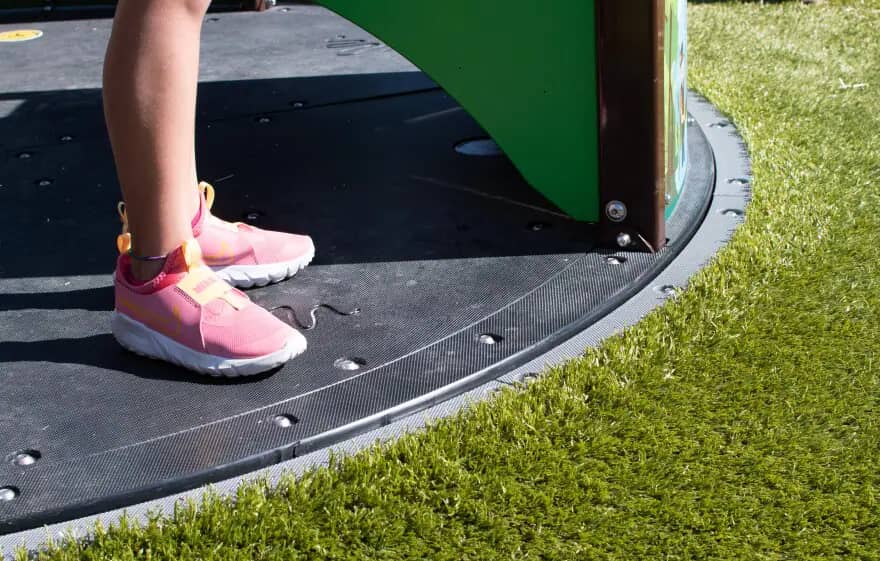 Soft turf surrounding the accessible merry-go-round at Wesselman Park