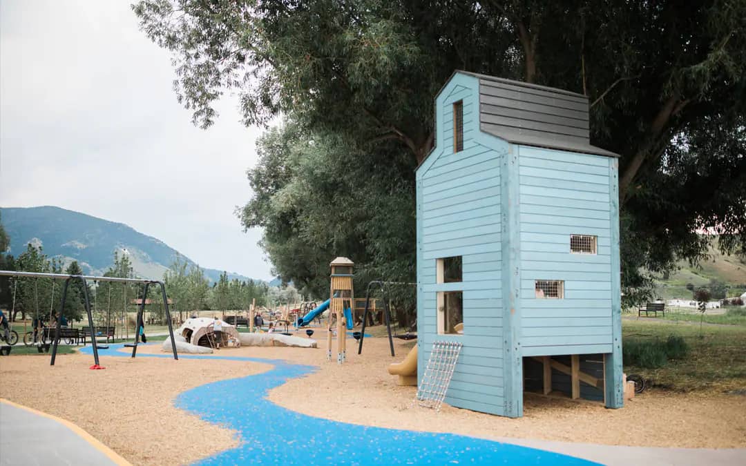 Wooden adventure playground with towers, swings, and mountain views at Story Mill Community Park in Bozeman